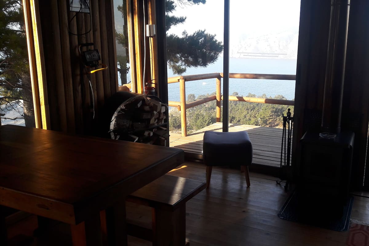 Una terraza de madera con vista al mar, una banca y una mesa.