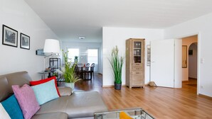 A modern living room with a sofa, coffee table, and dining area.