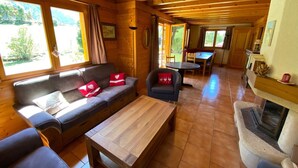 En mysig stuga med trägolv, en soffa, ett soffbord, en öppen spis och en matplats.