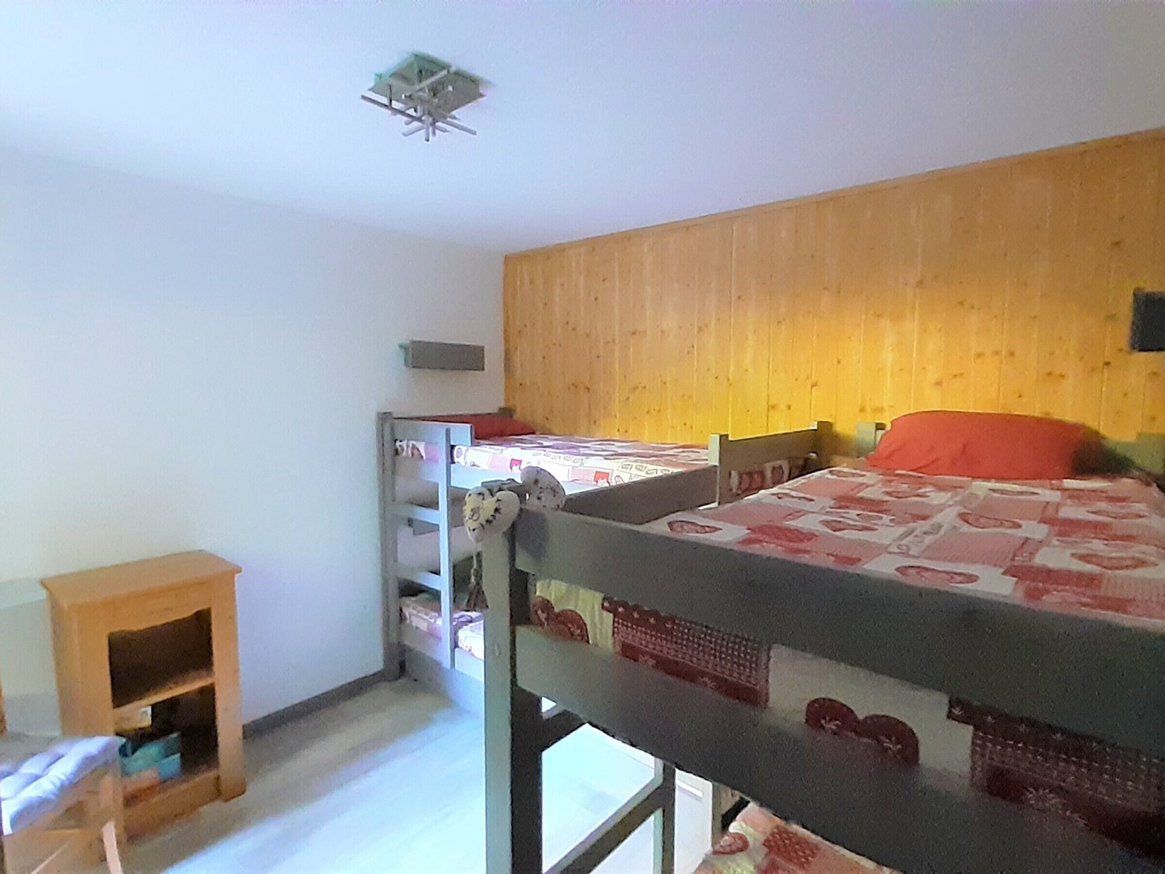 Ein Schlafraum mit Etagenbetten, einer Holzwand und einem kleinen Holzschrank.