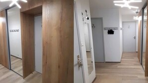Um corredor com piso de madeira, paredes espelhadas e iluminação no teto.