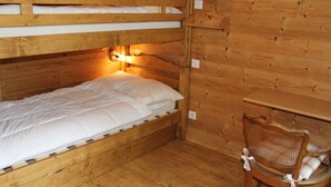 Una cama litera con cabecera de madera y un escritorio con silla.