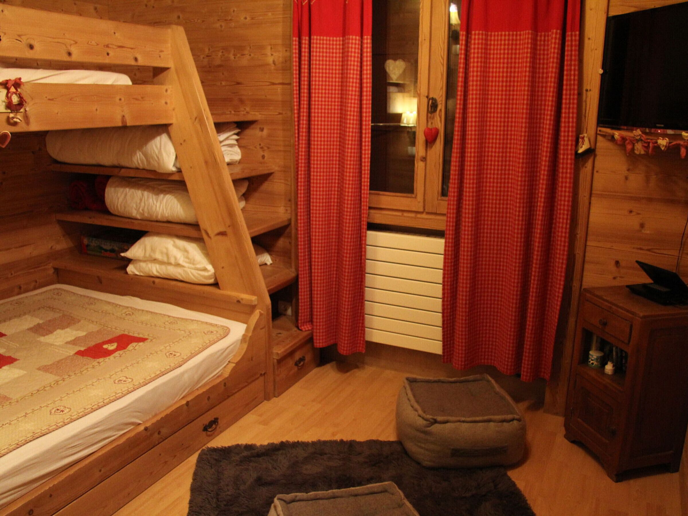 A cozy cabin-style room with a bunk bed, a small wooden cabinet, and a television on a wooden stand.