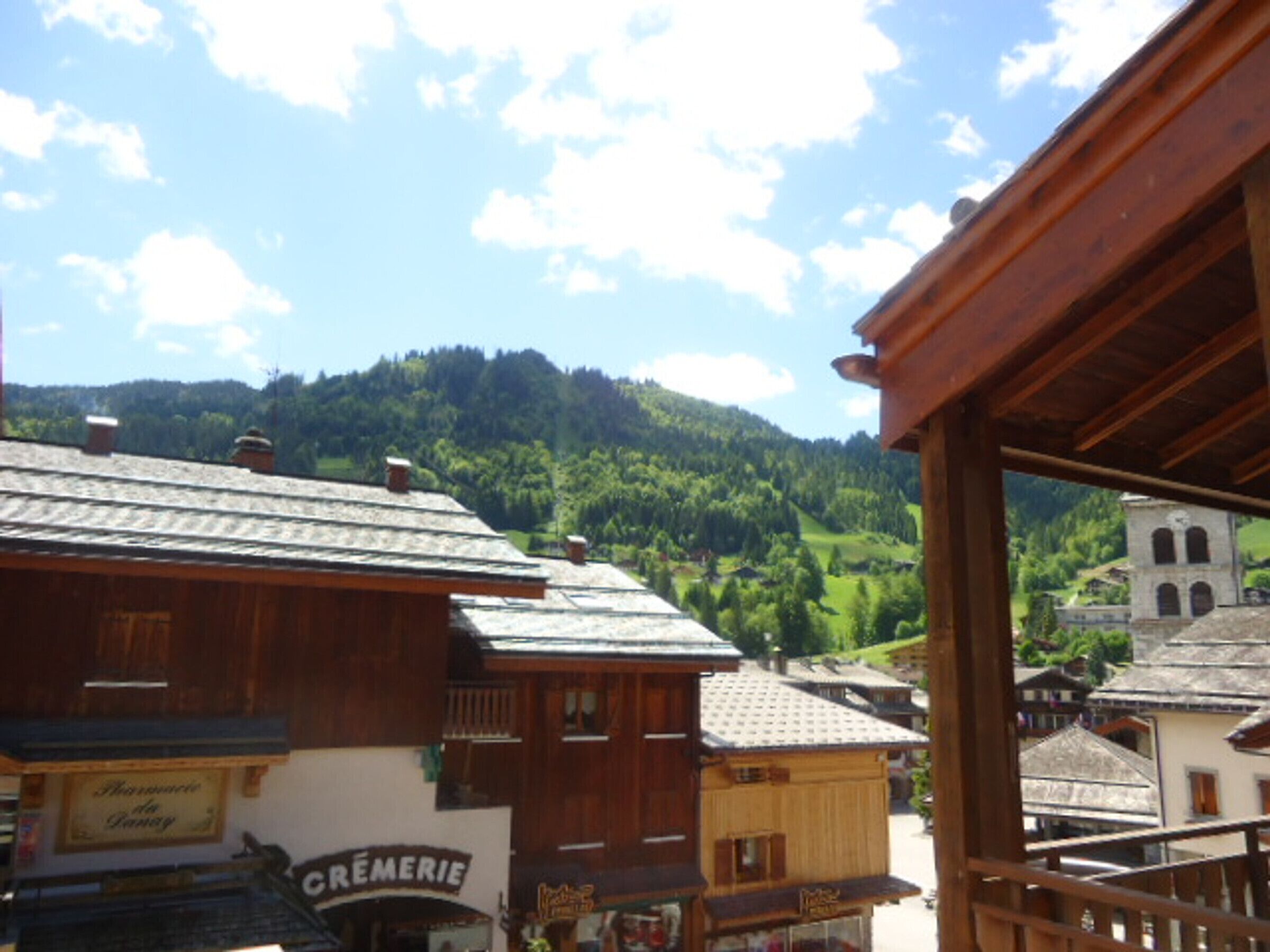 A wooden building with a sign that reads "CRÈMERIE" and a view of a mountainous landscape in the background.