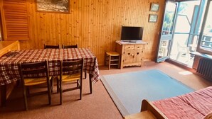 Une pièce en bois comprenant une table à manger, des chaises, un téléviseur et une fenêtre.