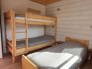 A bunk bed room with a wooden headboard, a small table, and a window. - 6 Personnes - Centre haut du village (OUB190) (La Clusaz)