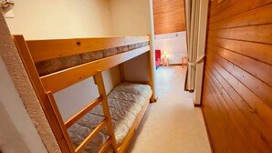 A bunk bed room with a wooden floor and a small table with a lamp. - Cozy Studio with Balcony, Near Ski Lift & Parking, La Clusaz (La Clusaz)
