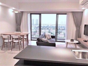 Un salon moderne comprenant un canapé, une table à manger, des chaises et un téléviseur.