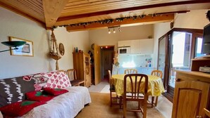 A cozy room with a bed, a dining table with chairs, a wooden cabinet, and a kitchenette in the background. - Simple duplex with parking in La Clusaz (La Clusaz)