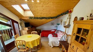 A cozy room with a wooden ceiling, a dining table with chairs, a bed with a red blanket, and a wooden cabinet. - Simple duplex with parking in La Clusaz (La Clusaz)