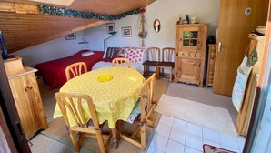 A cozy attic room with a wooden ceiling, a dining table with chairs, a red sofa, and a cabinet. - Simple duplex with parking in La Clusaz (La Clusaz)
