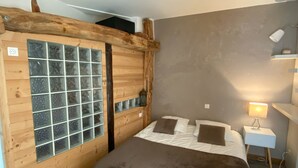 A bedroom with a wooden headboard, a bed with brown bedding, a white fluffy rug, and a nightstand with a lamp. - The 2 Alpes / Venosc, 10 pers. NEW with steam room, sauna, jacuzzi. (les deux alpes)
