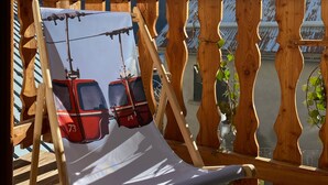 A wooden deck with a cushioned chair and a view of snow-capped mountains. - The 2 Alpes / Venosc, 10 pers. NEW with steam room, sauna, jacuzzi. (les deux alpes)
