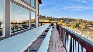A deck with picnic tables overlooking a hilly landscape.