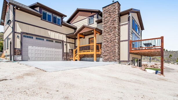 A two-story house with a garage, a stone chimney, and a wooden deck.