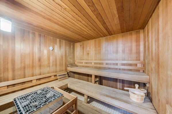 Una sauna con bancos de madera y un banco de metal.