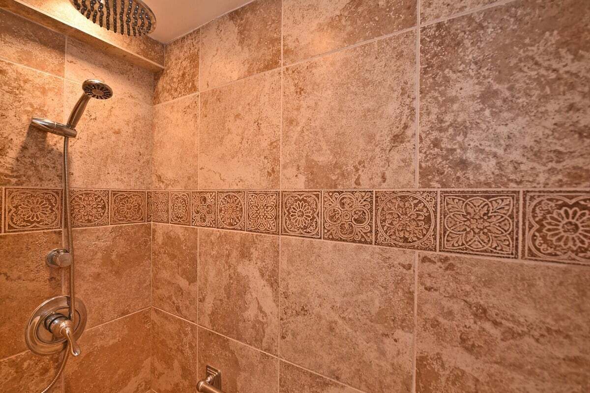 A shower with a handheld showerhead and a wall-mounted control valve.