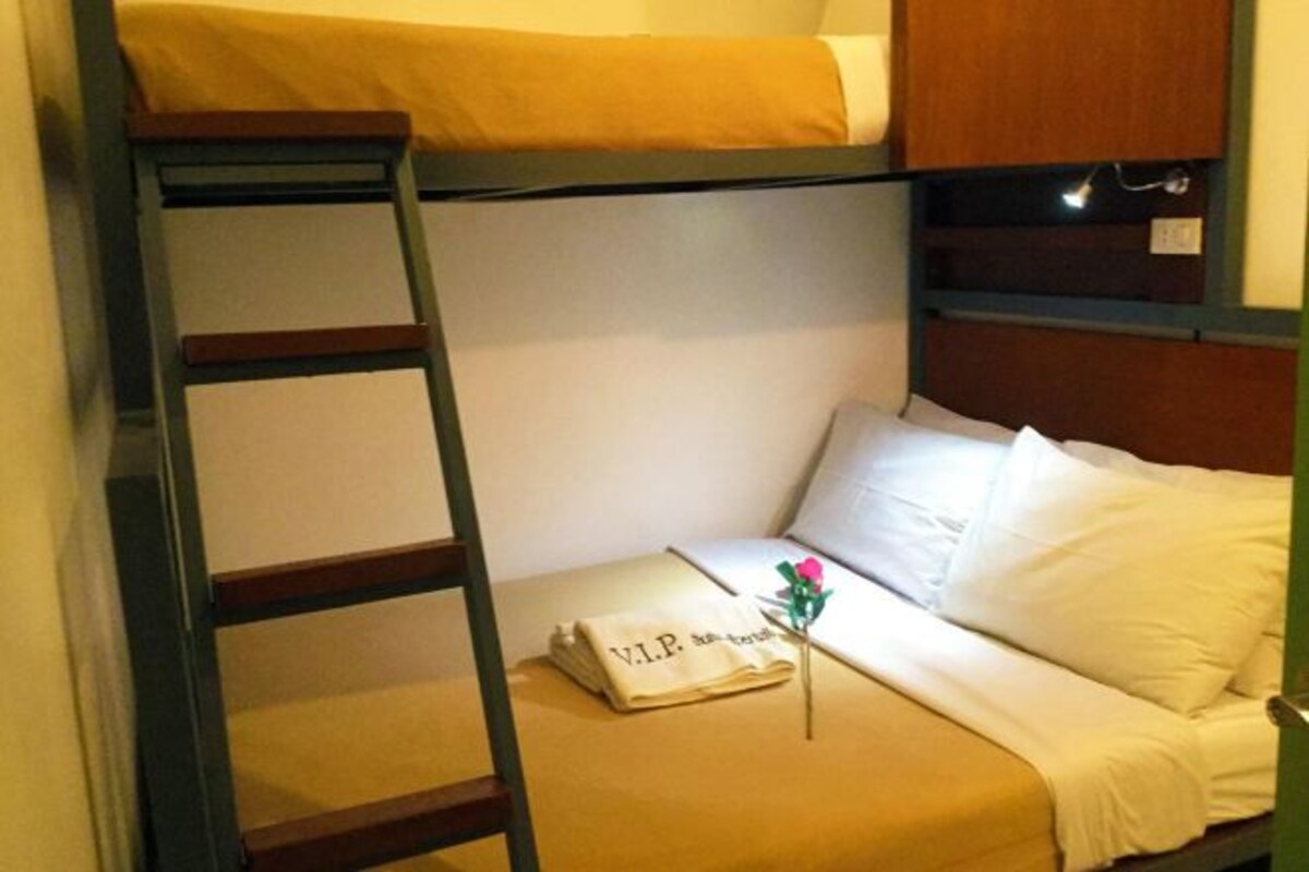 A bunk bed with a ladder, a bedside table with a folded towel, and a small decorative item.