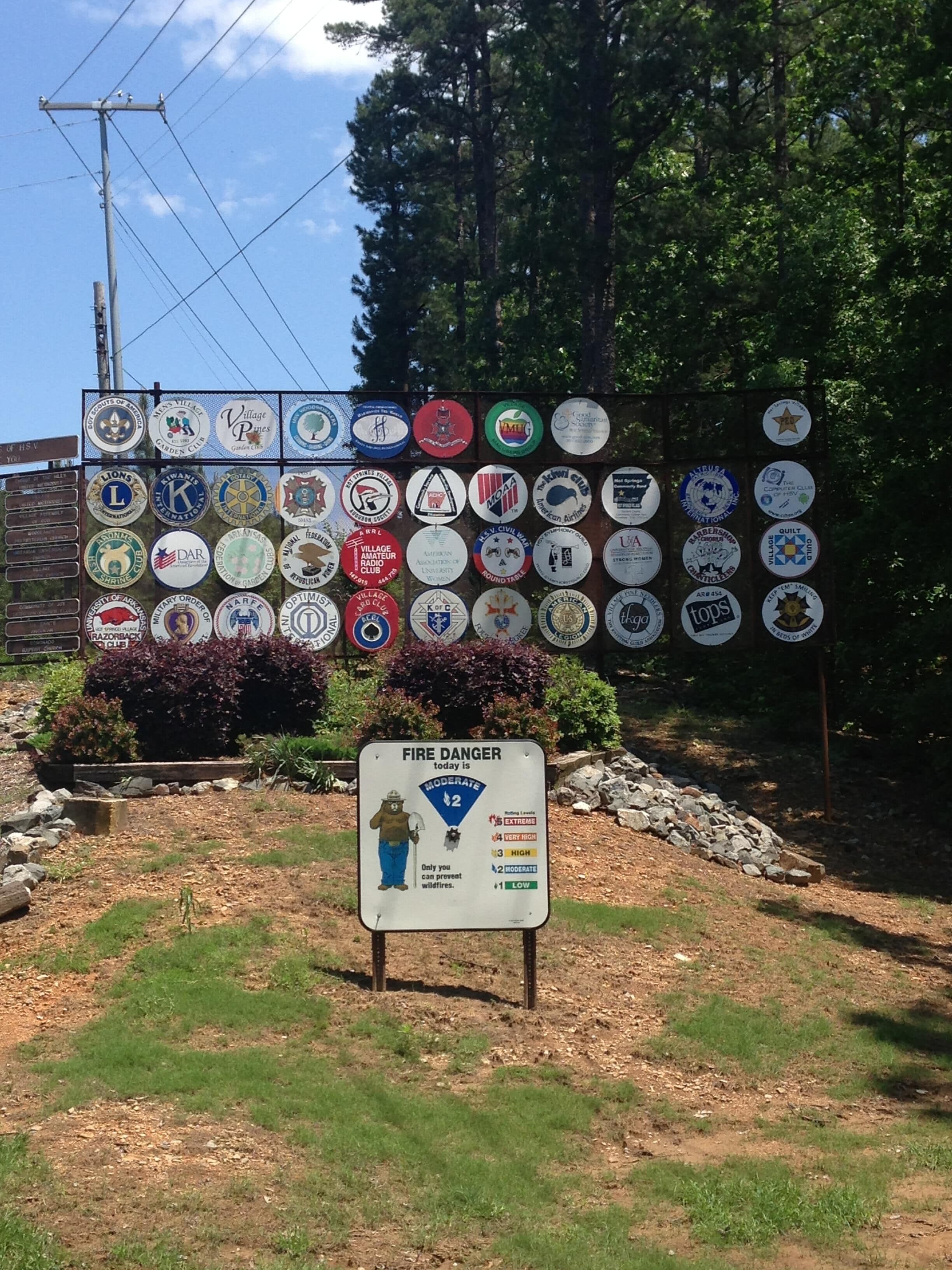 A sign with various badges and a fire danger rating sign.