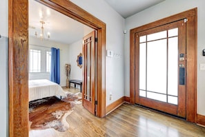 A room with a bed, a wooden door, and a light switch on the wall. - Classen Craftsman-near Asian & Paseo district (Oklahoma City)