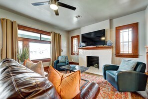 A living room with a leather sofa, blue armchairs, a fireplace, and a flat-screen TV.