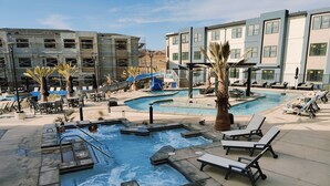 A pool area with multiple hot tubs, lounge chairs, and a slide. - St. George Gem, Pool, Hot Tub, View, Zion Basecamp (Hurricane)