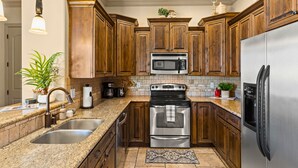 A kitchen with granite countertops, stainless steel appliances, wooden cabinets, and a backsplash. - St. George Gem, Pool, Hot Tub, View, Zion Basecamp (Hurricane)