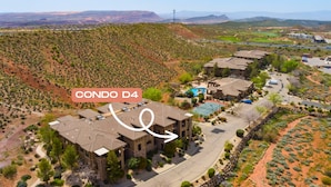 A large, multi-story building with a flat roof, surrounded by a landscaped area with trees and shrubs. - St. George Gem, Pool, Hot Tub, View, Zion Basecamp (Hurricane)