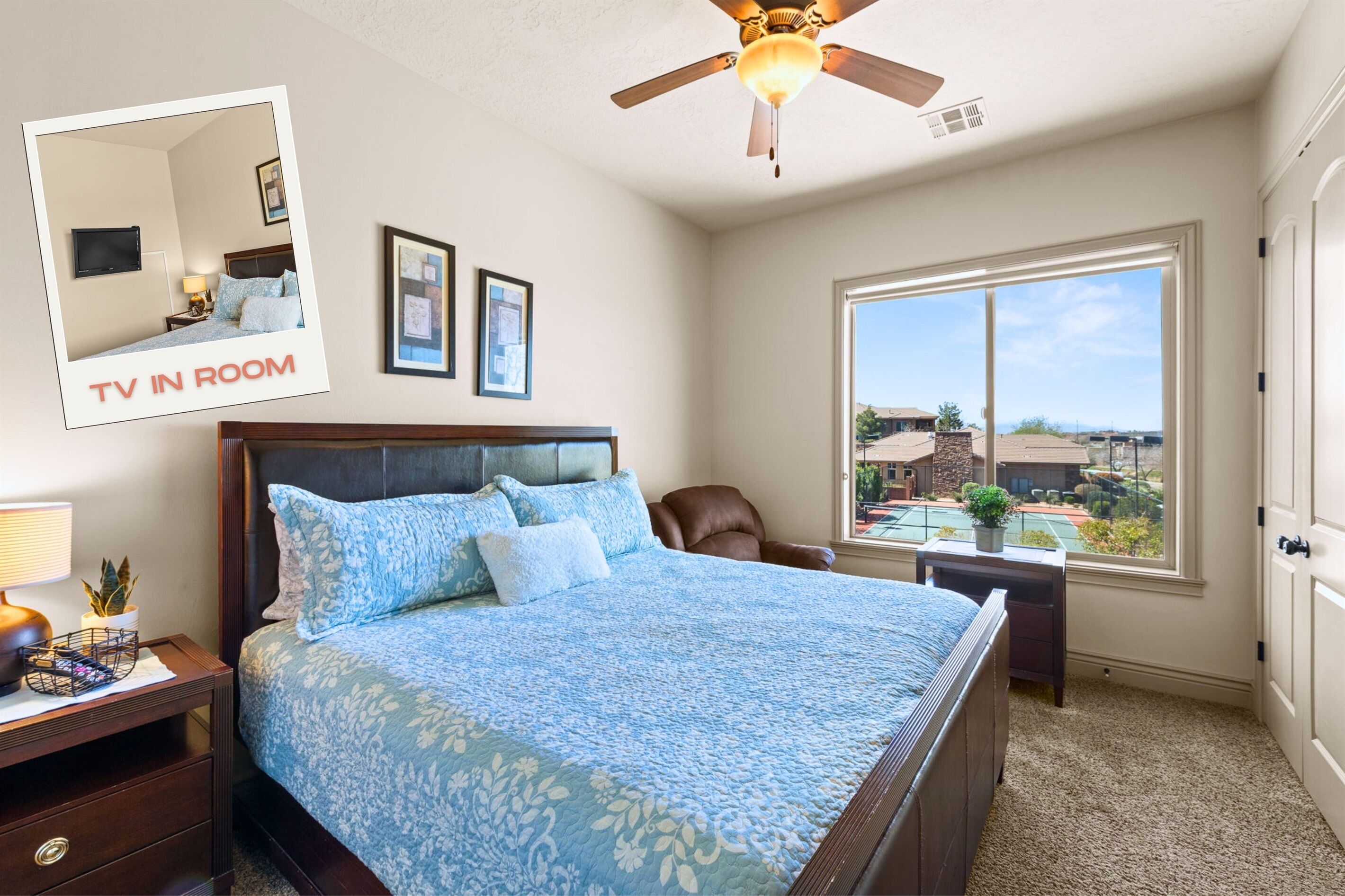 A bedroom with a large bed, a ceiling fan, a TV in the room, and a window with a view.