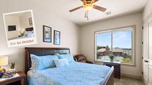 A bedroom with a large bed, a ceiling fan, a TV in the room, and a window with a view. - St. George Gem, Pool, Hot Tub, View, Zion Basecamp (Hurricane)