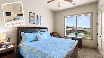 A bedroom with a large bed, a ceiling fan, a TV in the room, and a window with a view.
