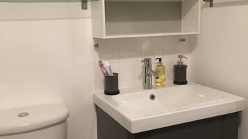 A modern bathroom with a white toilet, a white sink with a mirror above it, and a dark-colored cabinet below.