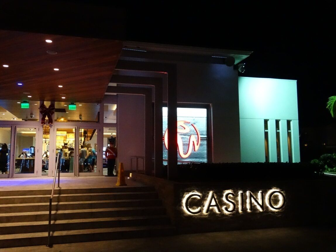 En casinoindgang med et neonskilt, trapper op til dørene og et stort vindue med en svane.
