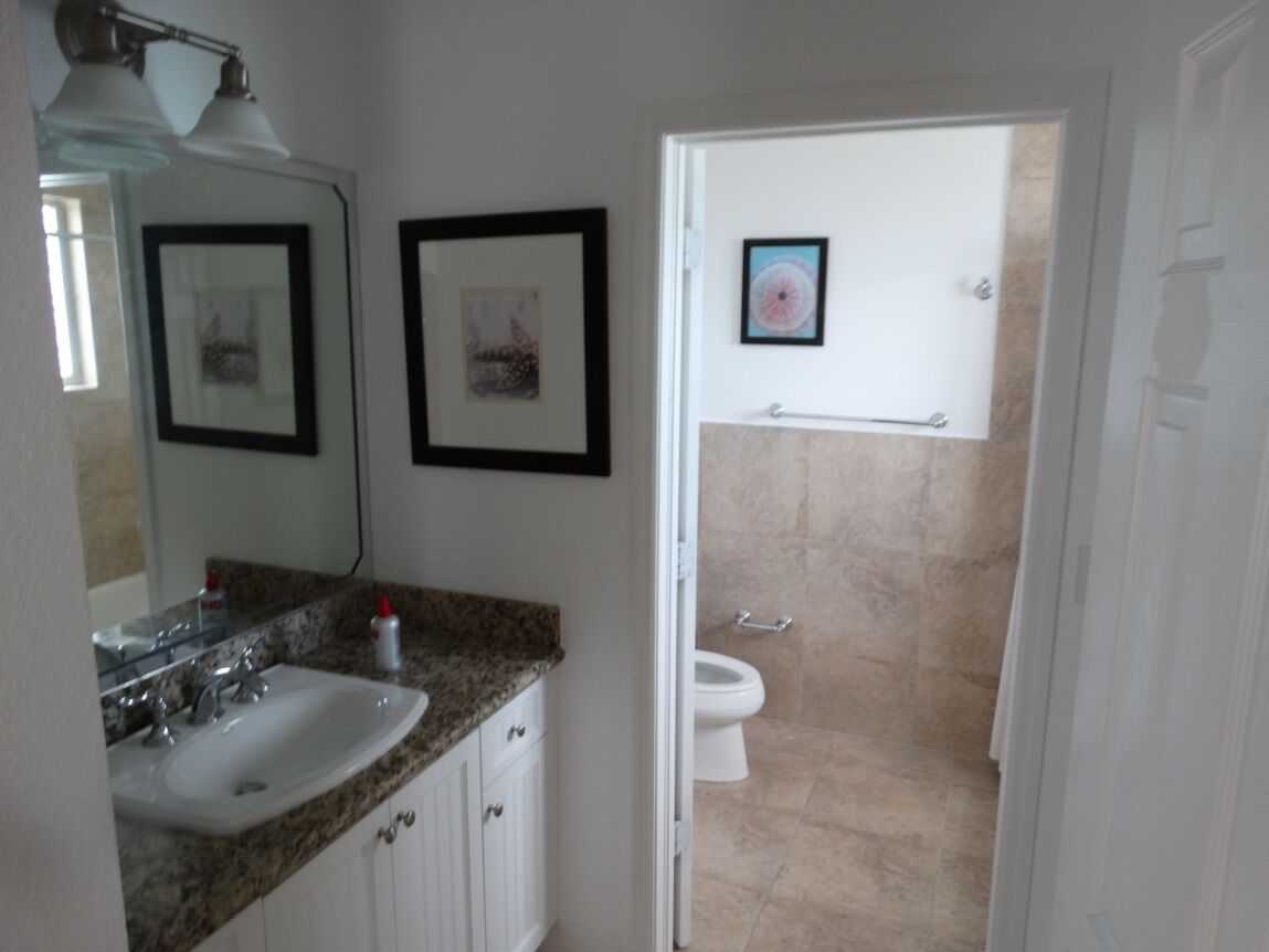 Un baño con lavamanos, espejo, cuadros enmarcados y retrete.