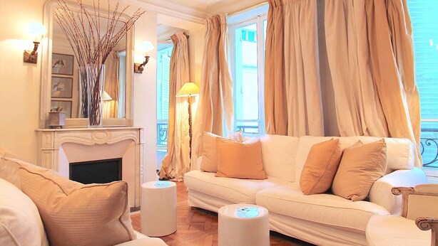 A living room with a white sofa, a white armchair, a round coffee table, and a fireplace. - Elegance in Saint Germain des Prés - Bonaparte - Left Bank (Paris)