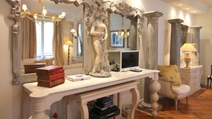 A room with a large ornate mirror, a statue, a desk with books, a computer, and a chair. - Elegance in Saint Germain des Prés - Bonaparte - Left Bank (Paris)