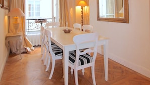 A dining area with a white table and chairs, a chandelier, and a large mirror on the wall. - Elegance in Saint Germain des Prés - Bonaparte - Left Bank (Paris)