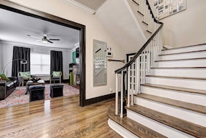 A staircase with wooden steps and white railings, a living room with a red patterned rug, a ceiling fan, and a view into another room through an open doorway. - Howes Capitol II-Sleek & spacious-walk to OU Med (Oklahoma City)