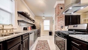 A kitchen with granite countertops, stainless steel appliances, and a patterned rug. - Howes Capitol II-Sleek & spacious-walk to OU Med (Oklahoma City)