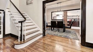 A staircase leading to a dining area with a chandelier, a kitchen in the background, and a rug on the floor. - Howes Capitol II-Sleek & spacious-walk to OU Med (Oklahoma City)