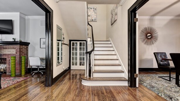A staircase with a white handrail and black steps, leading to a landing with a door. - Howes Capitol II-Sleek & spacious-walk to OU Med (Oklahoma City)