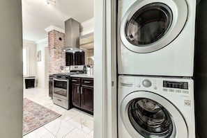 A kitchen with a brick wall, stainless steel appliances, and a tiled floor. - Howes Capitol II-Sleek & spacious-walk to OU Med (Oklahoma City)
