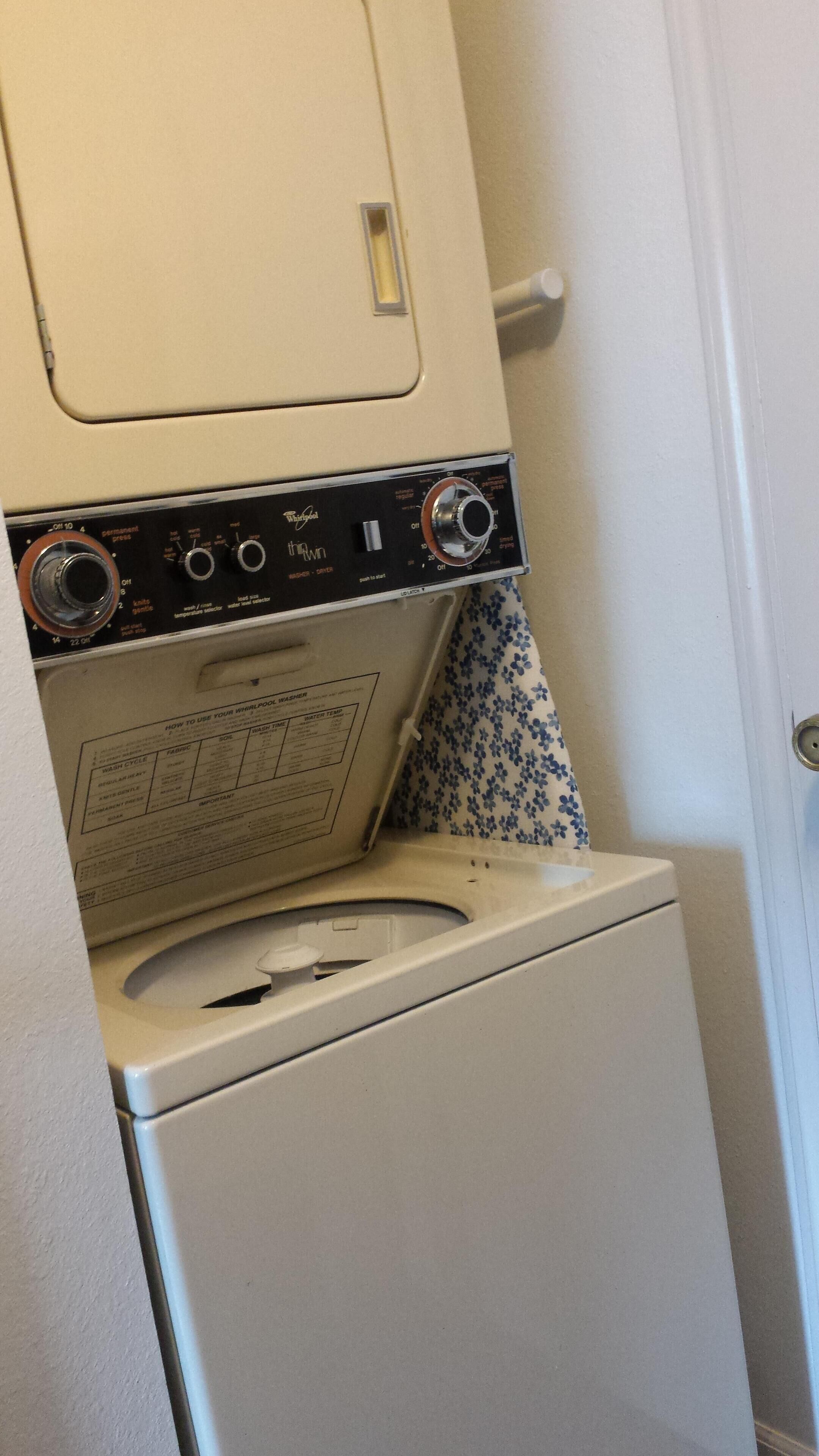 A front-loading washing machine with a control panel, a door, and a patterned wall.