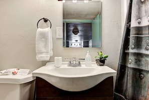 A bathroom with a white sink, a towel hanging on a ring, a mirror, and a potted plant.