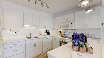 A modern kitchen with white cabinets, a microwave, a coffee maker, and a wooden crate with items on the counter.