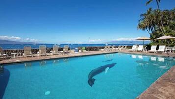 En pool med solstolar och utsikt över havet.