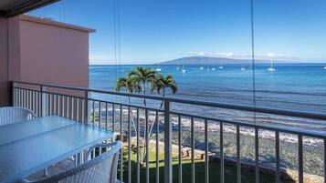 Un balcone con vista libera sul mare, un tavolo e delle sedie.