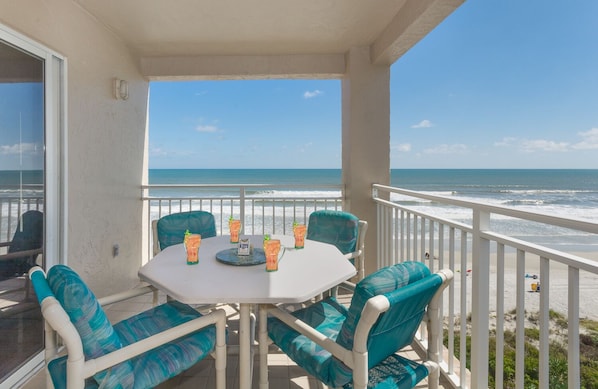 Un balcon avec une table et des chaises, donnant sur une plage.