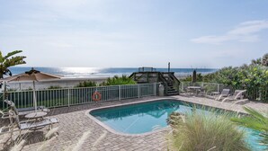 A pool area with a view of the ocean, a lifebuoy, and a gazebo.