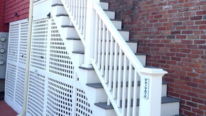 Un escalier avec des rampes blanches menant à une porte surmontée d’une fenêtre.
